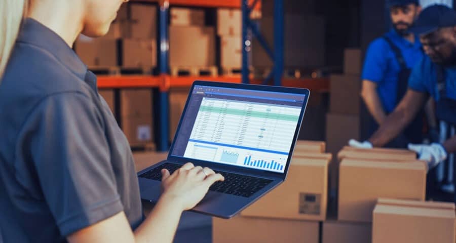 Inventory management software on a laptop in a warehouse setting.