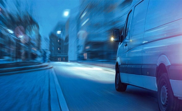 Rapid delivery van in motion through city streets, representing efficient logistics solutions from Banyan Technology.