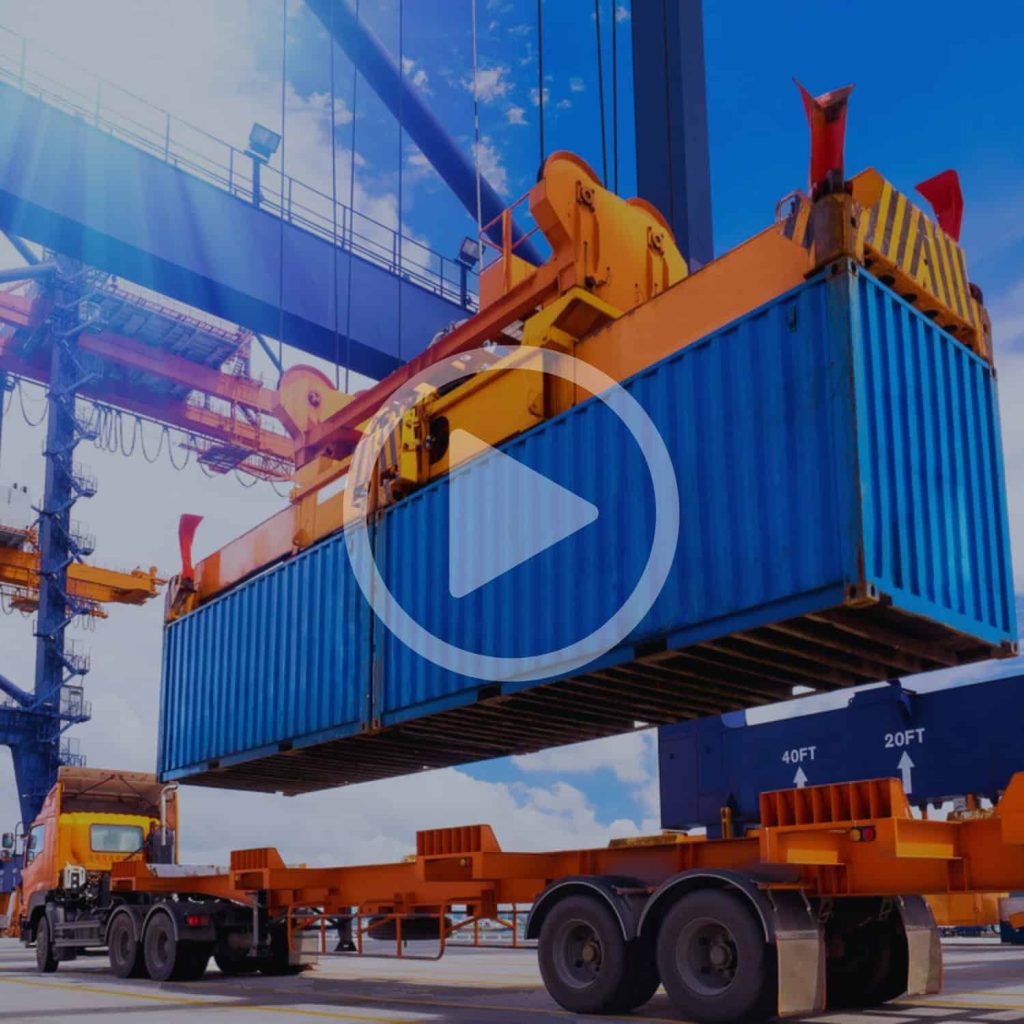 Loading container onto transport truck with heavy machinery at port or shipping yard for logistics and freight management.