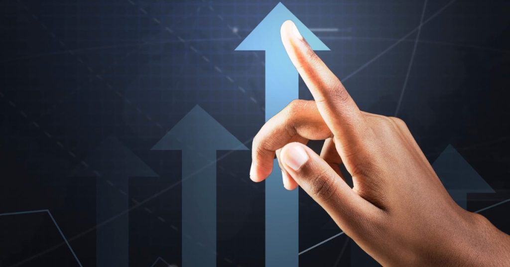 A woman's hand following an upwards arrow symbolizing growth and profitability.