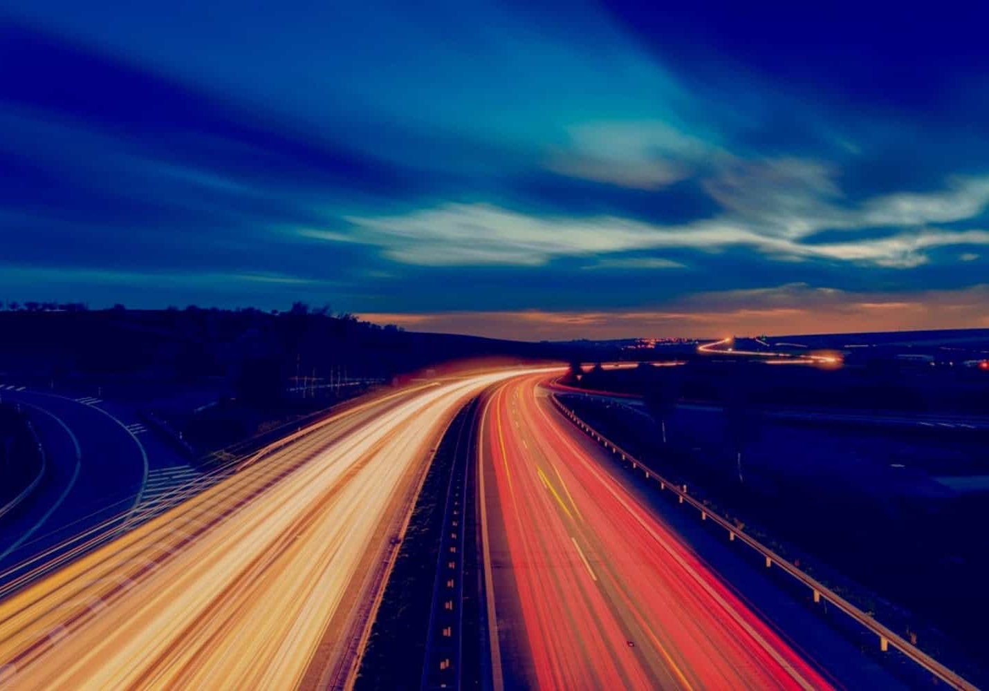 A multi-lane highway filled with streaks of vehicle lights at night
